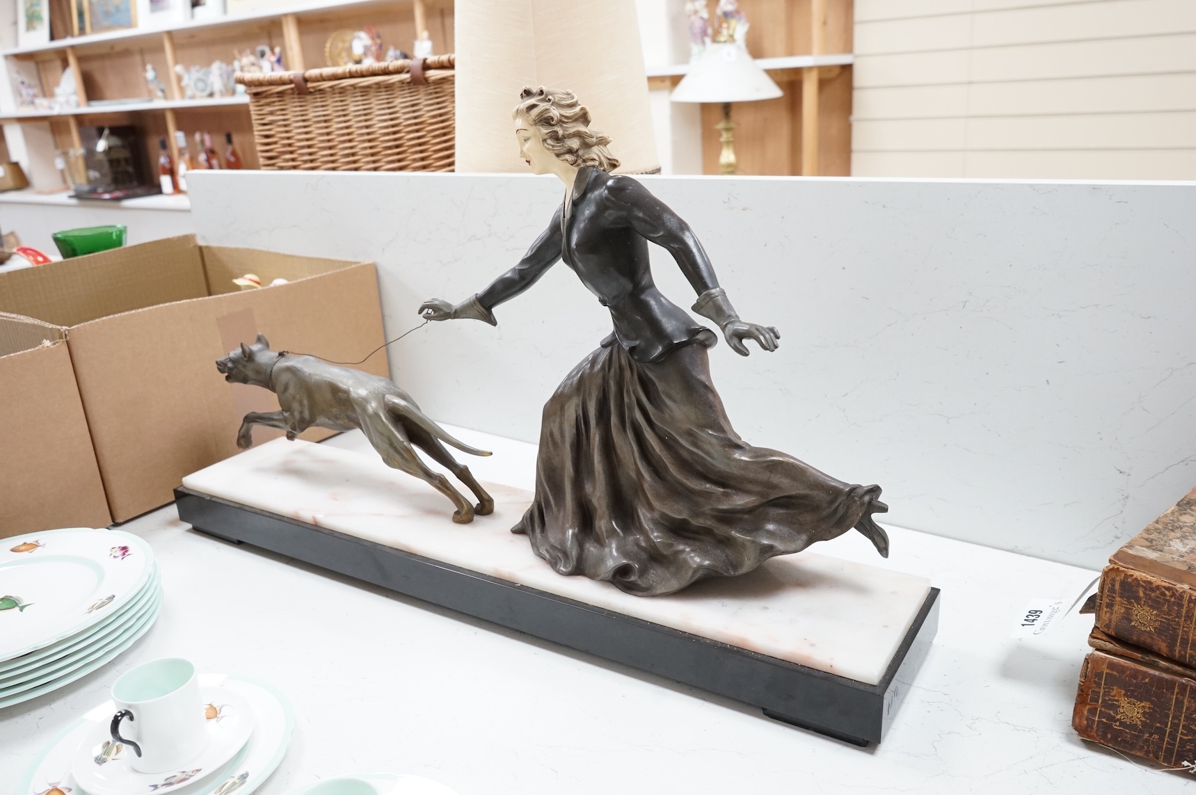 An Art Deco French spelter and ivorine model ‘Walkies Lady and Dog’, on a black marble and cream onyx base, 75cm long